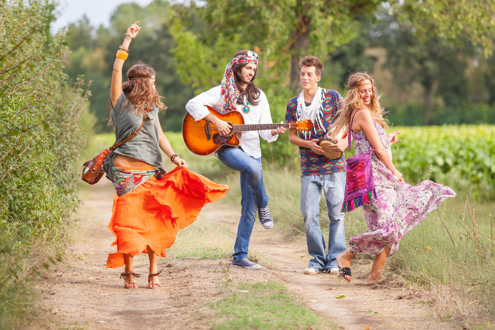Junge Leute tanzen und musizieren draußen. Flower Power Dekoration mieten: nachhaltige, flexible und professionelle Mietlösungen für Hochzeiten, Firmenfeiern und Festivals.